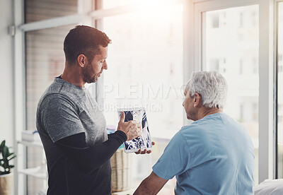 Buy stock photo Shot of a young male physiotherapist assisting a senior patient in recovery