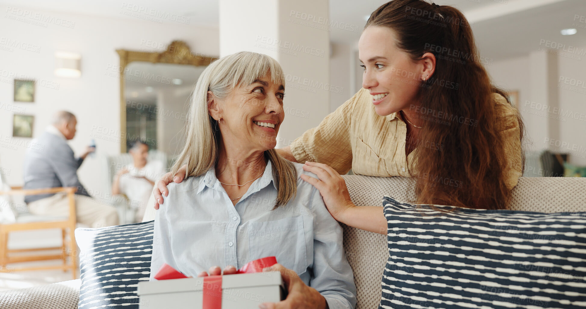 Buy stock photo Senior mom, daughter and gift in retirement home with shaking, joke or surprise on birthday. Women, family and present with wow, love and bonding on sofa for celebration with gratitude on mothers day