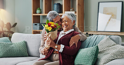 Old man, woman and surprise of flowers on couch or sofa, happy and couple in living room of house. Senior, male person and partner with gift for love, smile and happiness in home and retirement