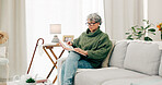 Woman reading funny book in living room for story, novel and knowledge in retirement. Happy senior female person relax with books in lounge for break, literature and hobby to enjoy on sofa at home
