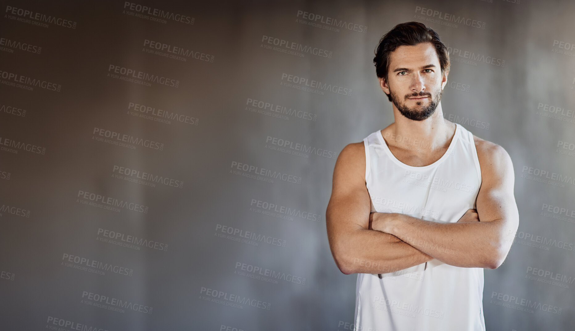 Buy stock photo Shot of a handsome young man standing with his arms folded in the gym