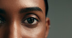 Eye, beauty and skincare with a woman on a gray background in studio closeup for cosmetics. Face, vision and natural care with a young person looking confident with her skin or facial treatment