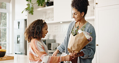 Kitchen, mother and girl with gift, flowers and present for birthday, love and family in house. Home, mom and daughter with embrace, happiness and cute in apartment, woman and child with smile