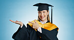 Pointing, graduation and portrait of woman on blue background for university, college and academy news. Student, school announcement and happy person for education, learning and studying in studio