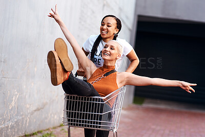 Buy stock photo Friends, happy and shopping cart in outdoor for play, funny and bonding together in city for freedom. Women, town and adventure in trolley for comedy, laughing and crazy happiness in urban on weekend