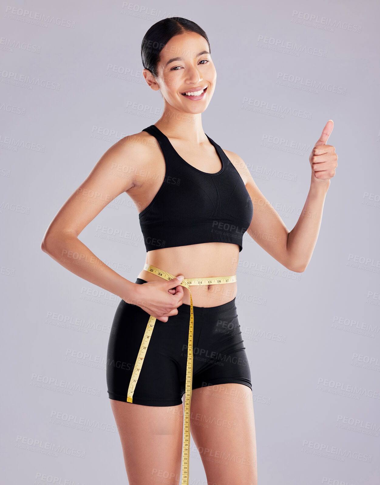 Buy stock photo Woman, stomach and thumbs up with tape measure in studio on white background for progress, weight loss and fitness. Female person, portrait and happy on workout with slimming for health and wellness