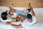 Happy mixed race family of four relaxing on the couch together in the lounge at home. Cheerful brother and sister laughing spending time with parents. Mother and father bonding with their children