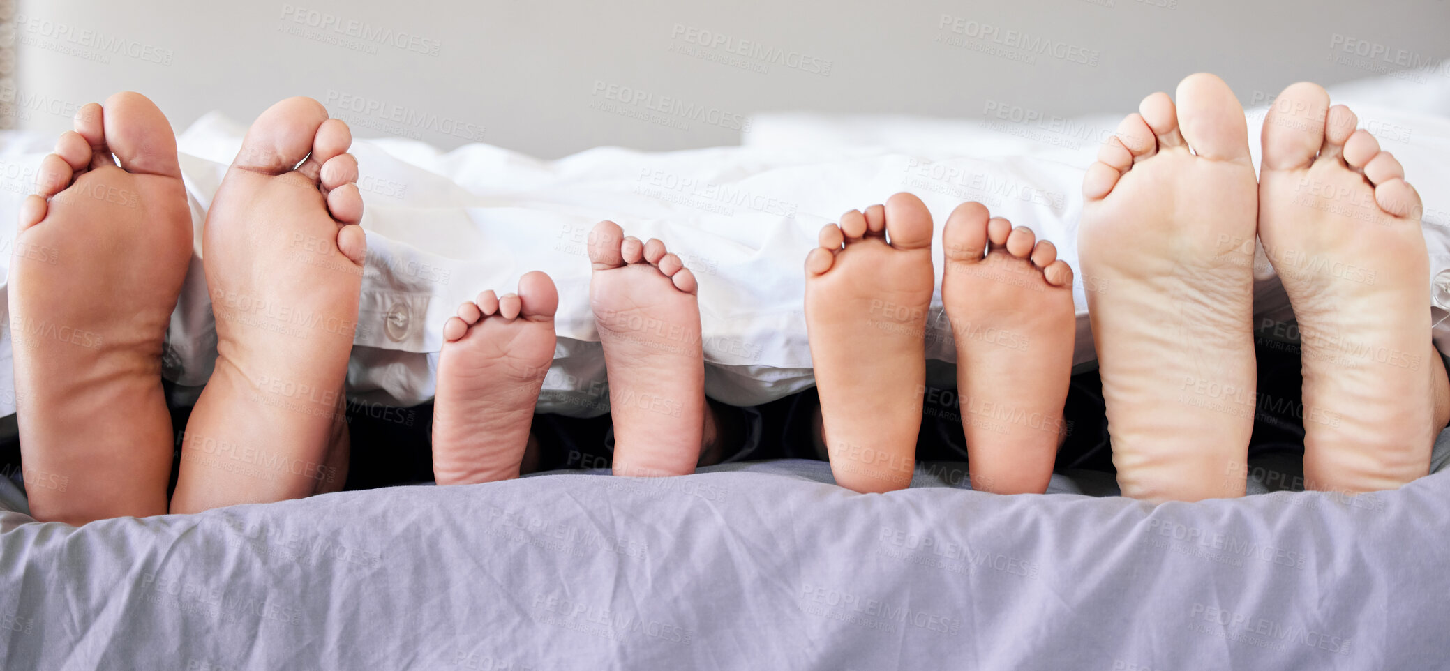 Buy stock photo Feet, family and relax in bed on weekend for comfort, love and support or care in new home. Mom, dad and children with peace, calm and resting in apartment or house for vacation or sleeping together