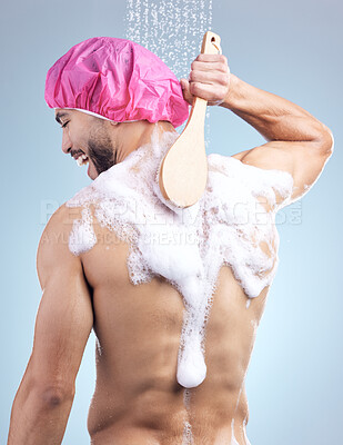 Buy stock photo Shower washing, soap and man with brush for cleaning, skincare and fresh morning routine on blue background. Health, wellness and male person in water for grooming, cap or hygiene in studio from back