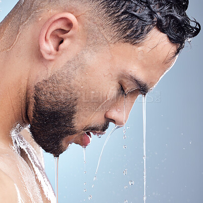 Buy stock photo Man, shower and water on face for skincare with washing body, hygiene wellness and skin glow in studio. Male person, liquid drops and closeup cleaning for grooming with health by blue background