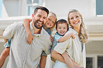 Portrait of happy parents giving their little children piggyback rides outside in a garden. Smiling caucasian couple bonding with their adorable son and daughter in the backyard. Playful kids enjoying