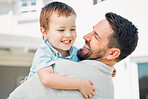 Happy caucasian father holding and comforting cheerful son while having fun in the sun outside. Smiling man carrying carefree boy while bonding in the yard. Loving dad enjoying quality time with kid