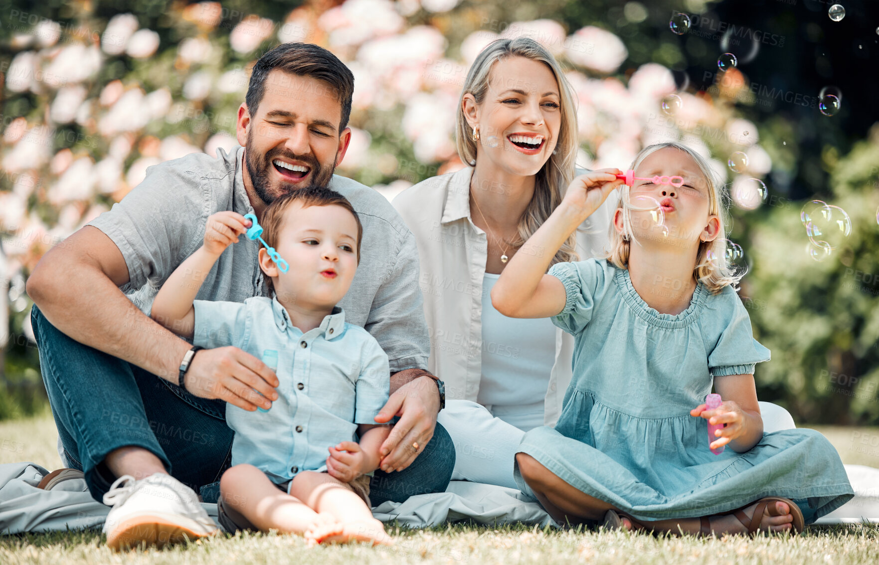 Buy stock photo Happy, family and blowing bubbles in garden at home with fun, bonding and support with care. Parents, kids and smile or laugh for child development or growth in outdoor with love and security