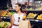 Shopping, holding and looking at fruit at shop, buying healthy food and examining items at a grocery store. Woman deciding, choosing and picking ripe, fresh and delicious produce at a market