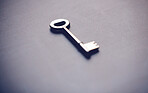 Above shot of a key on a grey table in studio. This is a symbol of opportunity or new beginnings. Unlock your potential and open doors. The idea here is promotion, advancement and success in business