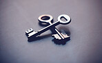 Above shot of two keys lying crossed on a table in studio. Can symbolise unlocking doors or opportunities. Could show the key to success or promotion. The key to your growth is different from the next