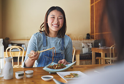 Buy stock photo Japanese, food and woman at a restaurant eating for dinner or lunch meal using chopsticks and feeling happy with smile. Plate, date and person enjoy Asian cuisine, noodles or diet at a table