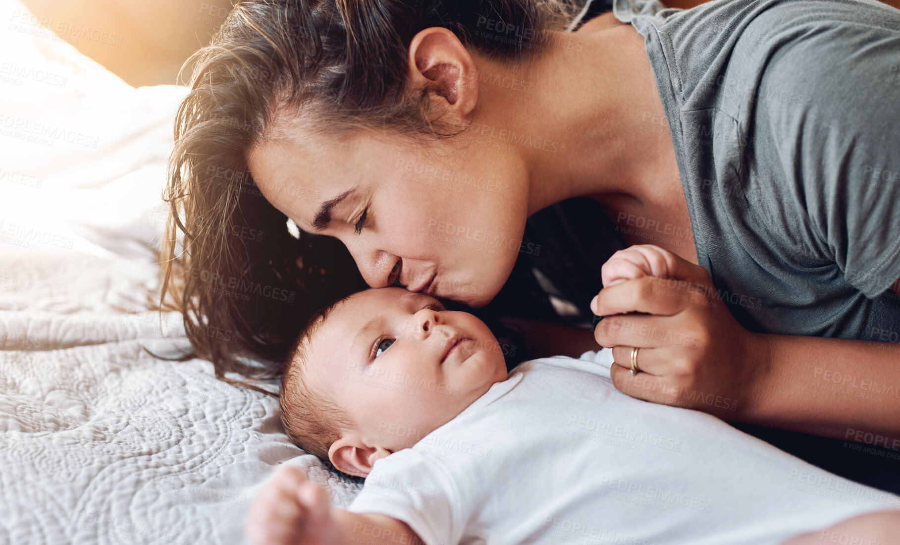 Buy stock photo Mom, baby and forehand kiss on bed in home for support, love and care for growth and child development. Parent, kid and happy in bedroom with playing for bonding, childhood memories and toddler