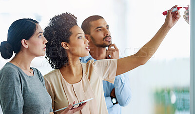 Buy stock photo Business people, writing and thinking with tablet for planning, tasks or agenda on glass board at office. Group of young and creative employees taking notes for discussion, brainstorming or startup