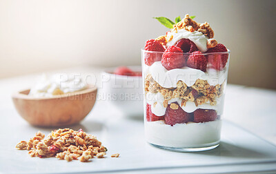 Buy stock photo Yogurt, container and glass with fruit in cereal for breakfast food, nutrition and healthy meal on plate. Table, dairy and raspberry in bowl with wellness for morning, organic snack and vegan diet