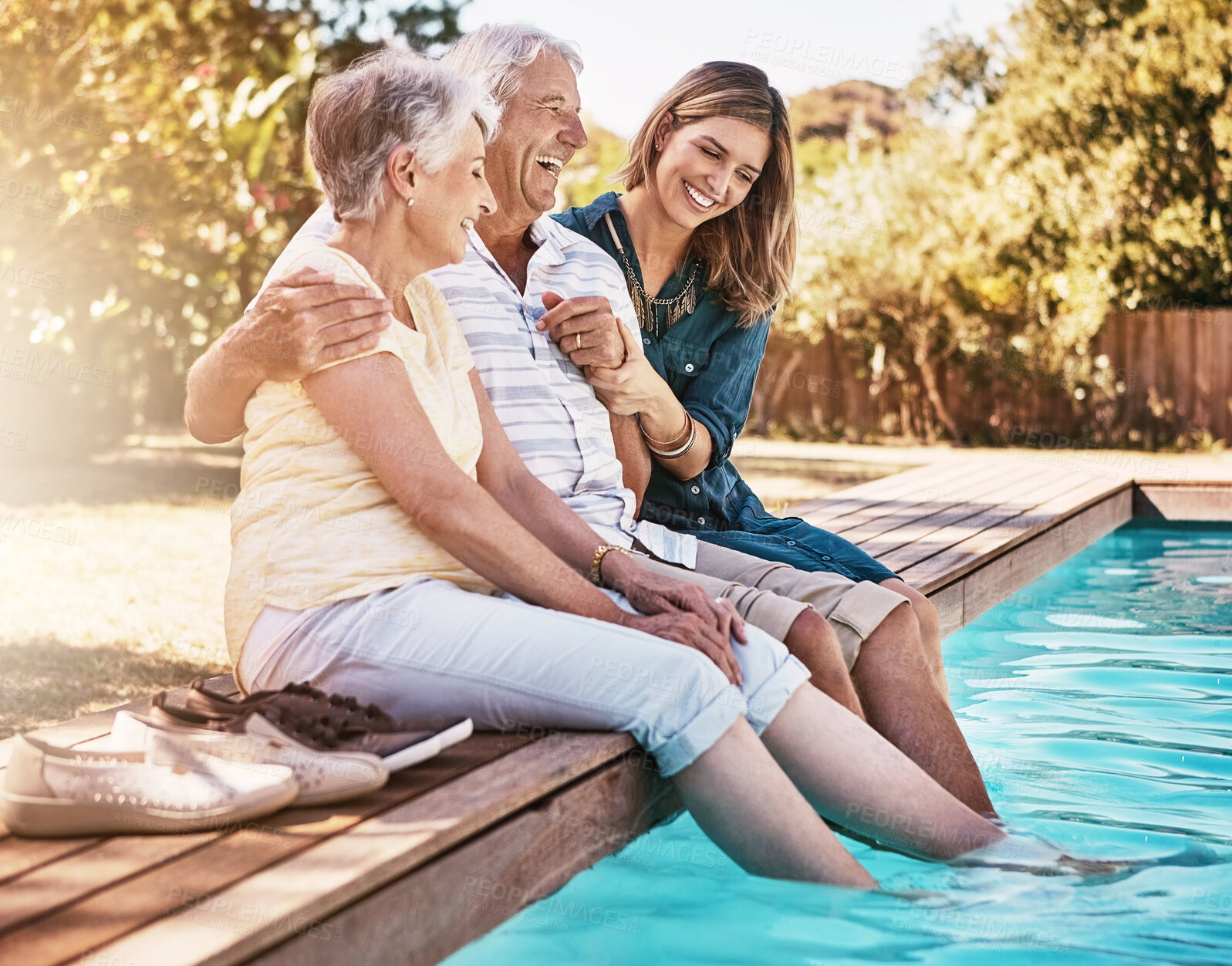 Buy stock photo Happy, family and people hugging in pool for bonding, care and support on summer holiday with lens flare. Smile, senior parents and adult daughter with love embrace at home for wellness and relax