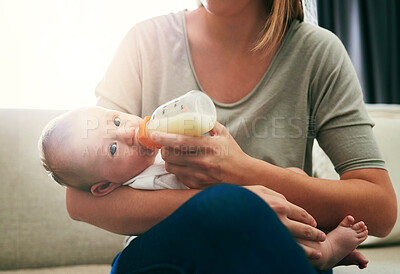 Buy stock photo Mom, milk and feeding baby in living room for growth development, nutrition or digestive health. Lens flare, formula and woman with infant child for drinking, wellness or bonding with bottle in home
