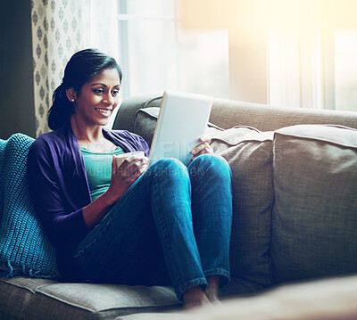 Buy stock photo Home, Indian woman and tablet on sofa for fun, relax and ebook reading with technology in living room. Apartment, happy girl and digital for streaming comedy, film and watch movie with coffee cup