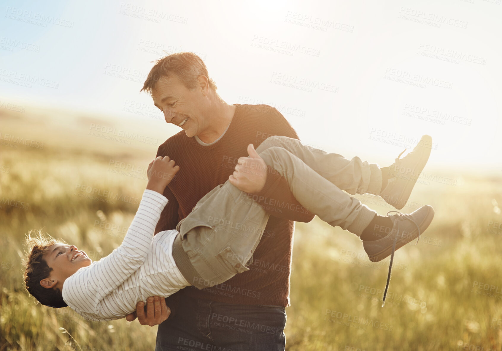 Buy stock photo Countryside, family or love with father and son having fun outdoor in field together for bonding. Carry, happy or smile with single parent man and boy child in nature for game, leisure or summer