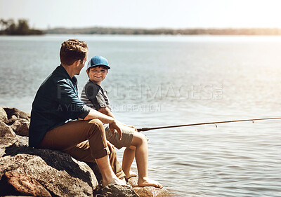 Buy stock photo Happy father, fishing and teaching son with rod on rock by beach, lake or ocean in nature. Dad with child, kid or little boy enjoying bonding, lesson or tips to catch sea creatures or animal in water