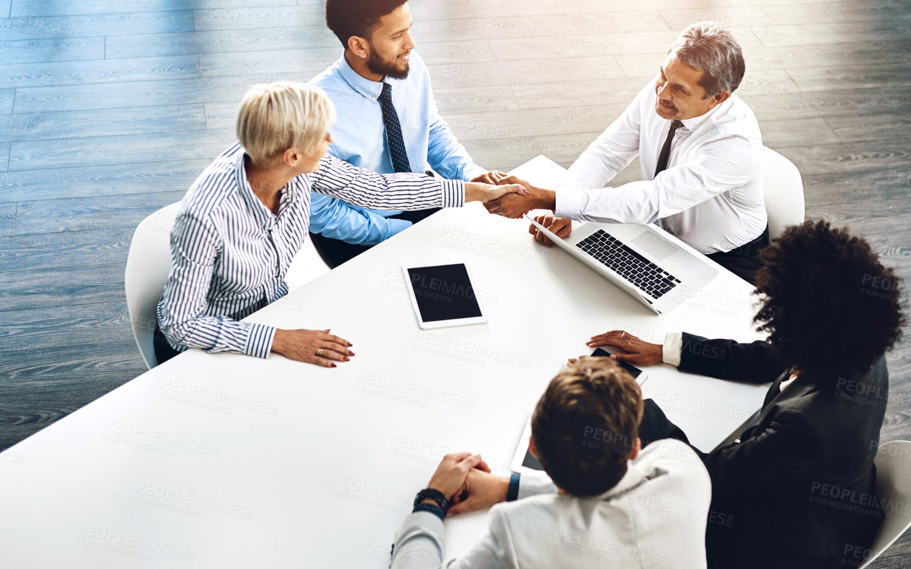 Buy stock photo Handshake, meeting and technology with business people in boardroom of office together from above. Agreement, deal or merger with man and woman employee shaking hands in workplace for partnership