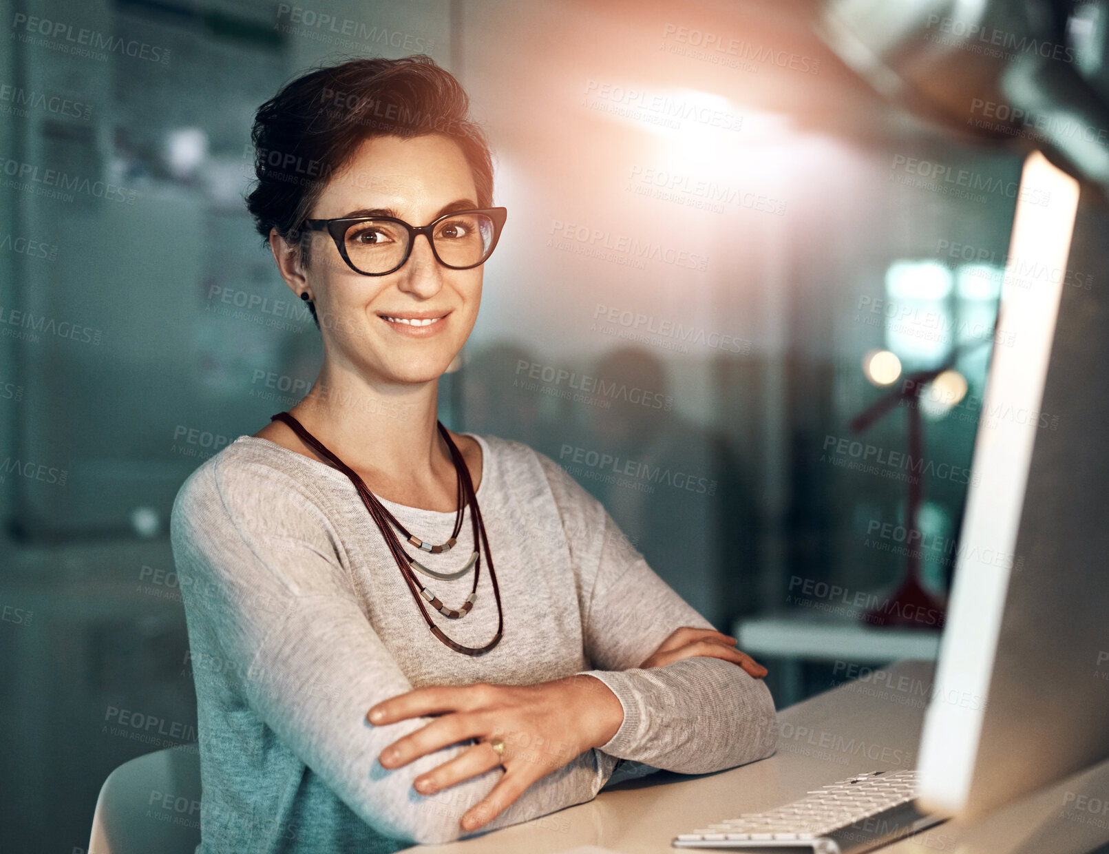 Buy stock photo Portrait, female designer and computer at night with glasses, confident and deadline in office. Overtime, happy woman and technology at desk for research, positive review or arms crossed in workplace