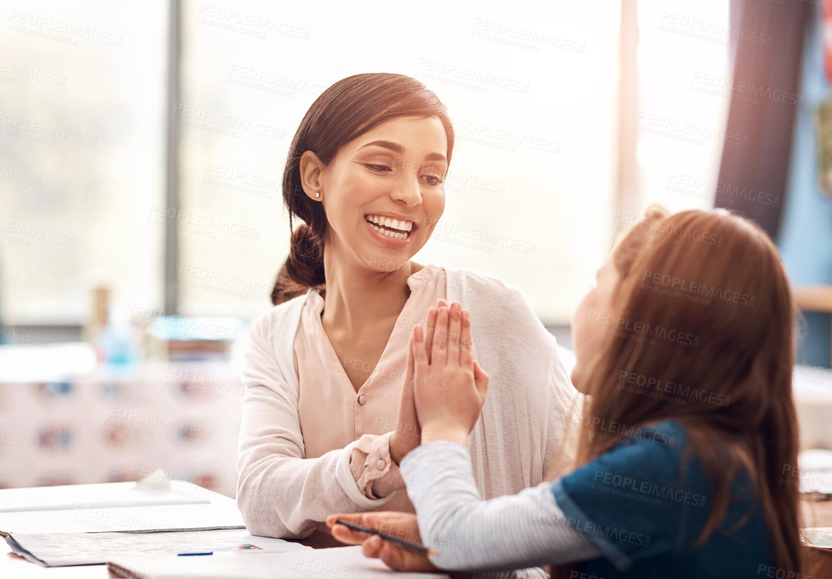 Buy stock photo Education, woman and student in classroom with high five, success and achievement at school. Happy, female teacher and girl with support for development, progress and help at table with notebook