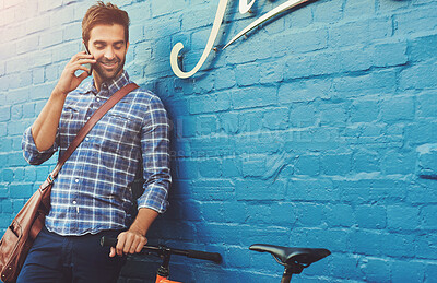 Buy stock photo Talking, phone call and happy man on bicycle in city for eco friendly transportation by brick wall. Mobile, conversation and person with bike for communication, travel and commute by space outdoor