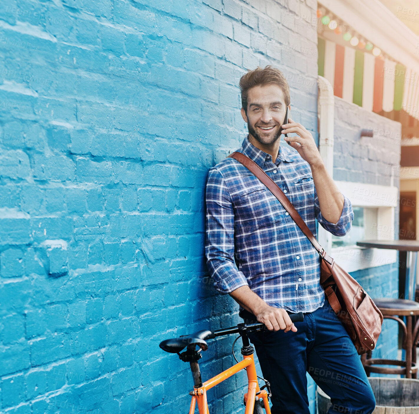 Buy stock photo Portrait, phone call and happy man on bicycle in city for eco friendly transportation by brick wall. Mobile, conversation and person with bike for communication, travel and commute by space outdoor