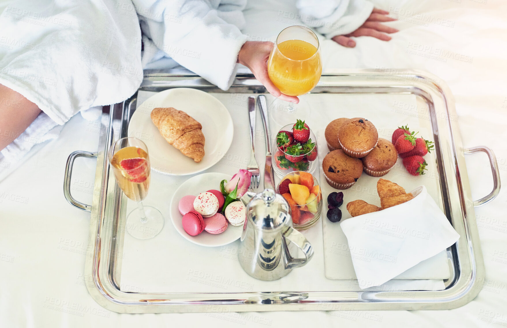 Buy stock photo Vacation, hands and food in bed for breakfast, hospitality and comfort in morning. Person, pastry and fruits with orange juice for meal, room service and hungry guest in bedroom of Spain hotel