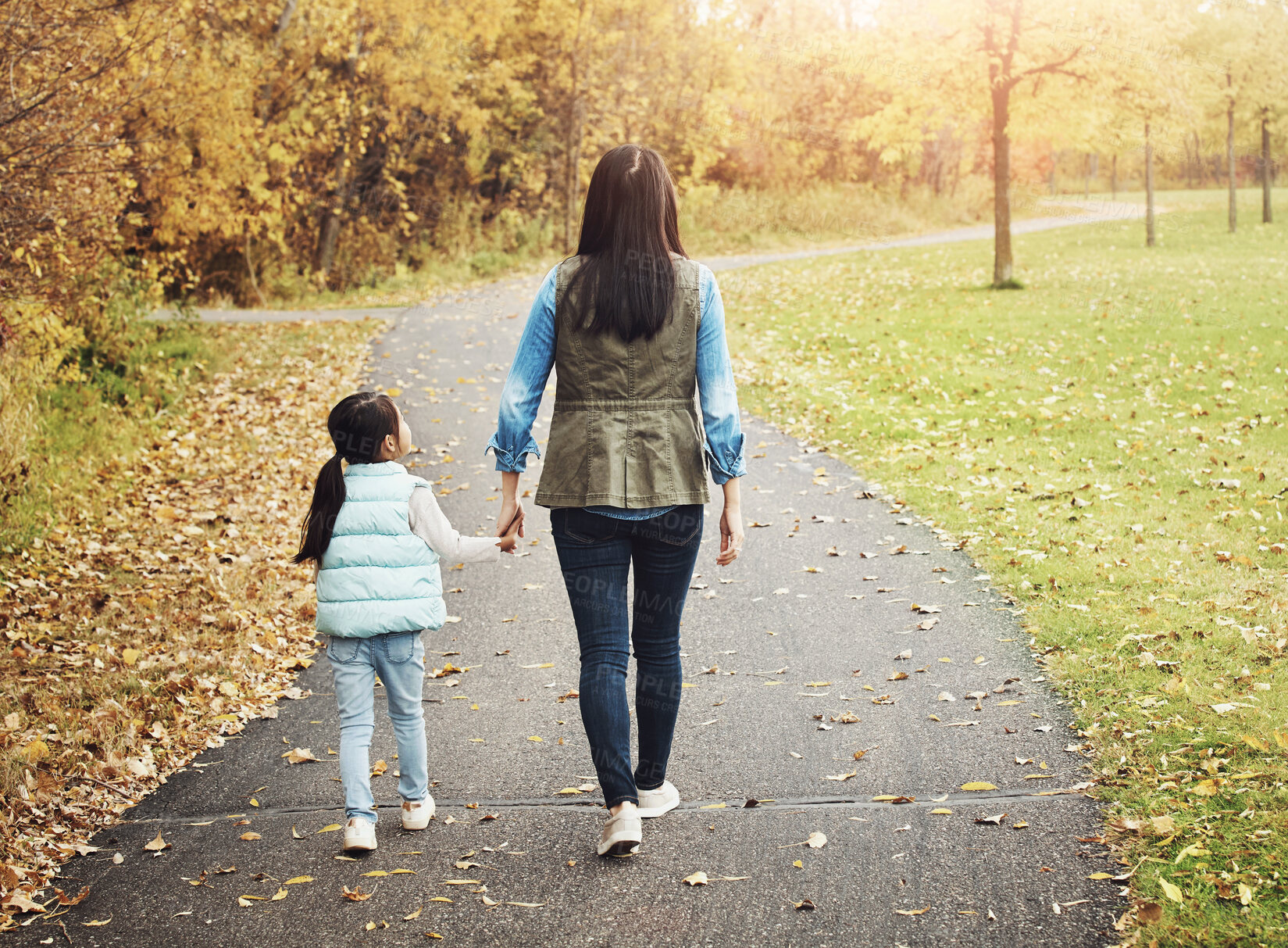 Buy stock photo Walking, nature and back of mother with child in outdoor park for bonding together in Autumn. Holding hands, field and mom with girl kid at garden for playing, fun and family time on weekend.