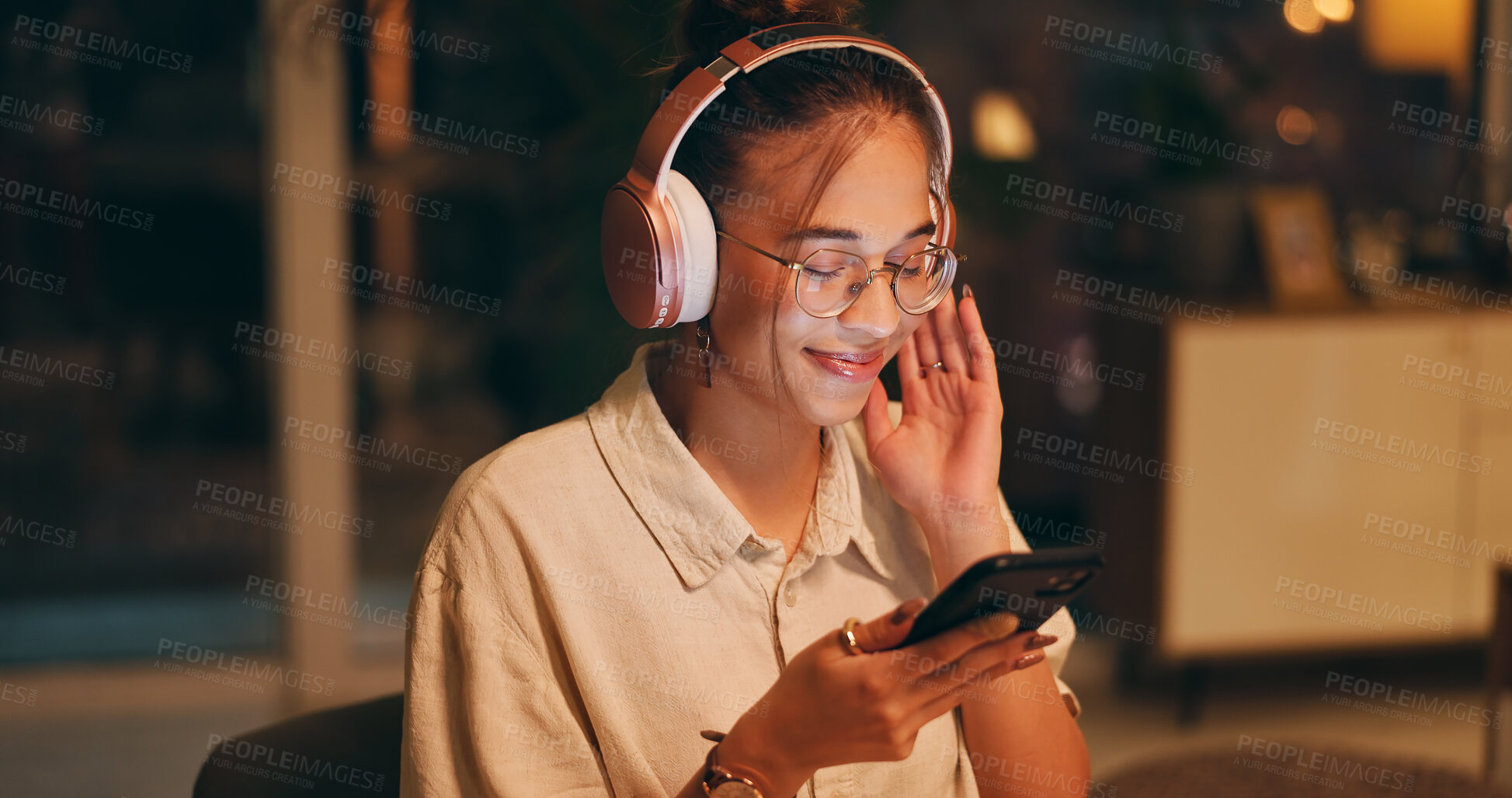 Buy stock photo Smartphone, happy woman and night for remote work with headphones, enjoy and listening to music. Female designer, overtime and technology at home for podcast, streaming and entertainment in apartment