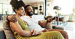 Love, hug and happy couple watching tv on sofa with remote control for movie, choice or film search at home. Relax, television and people embrace in a living room with cable service entertainment