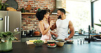 Happy, couple and feeding with food in kitchen for meal prep, bonding and support in cooking. Vegan, man and woman with eating to taste at home for healthy diet, nutrition and love in marriage