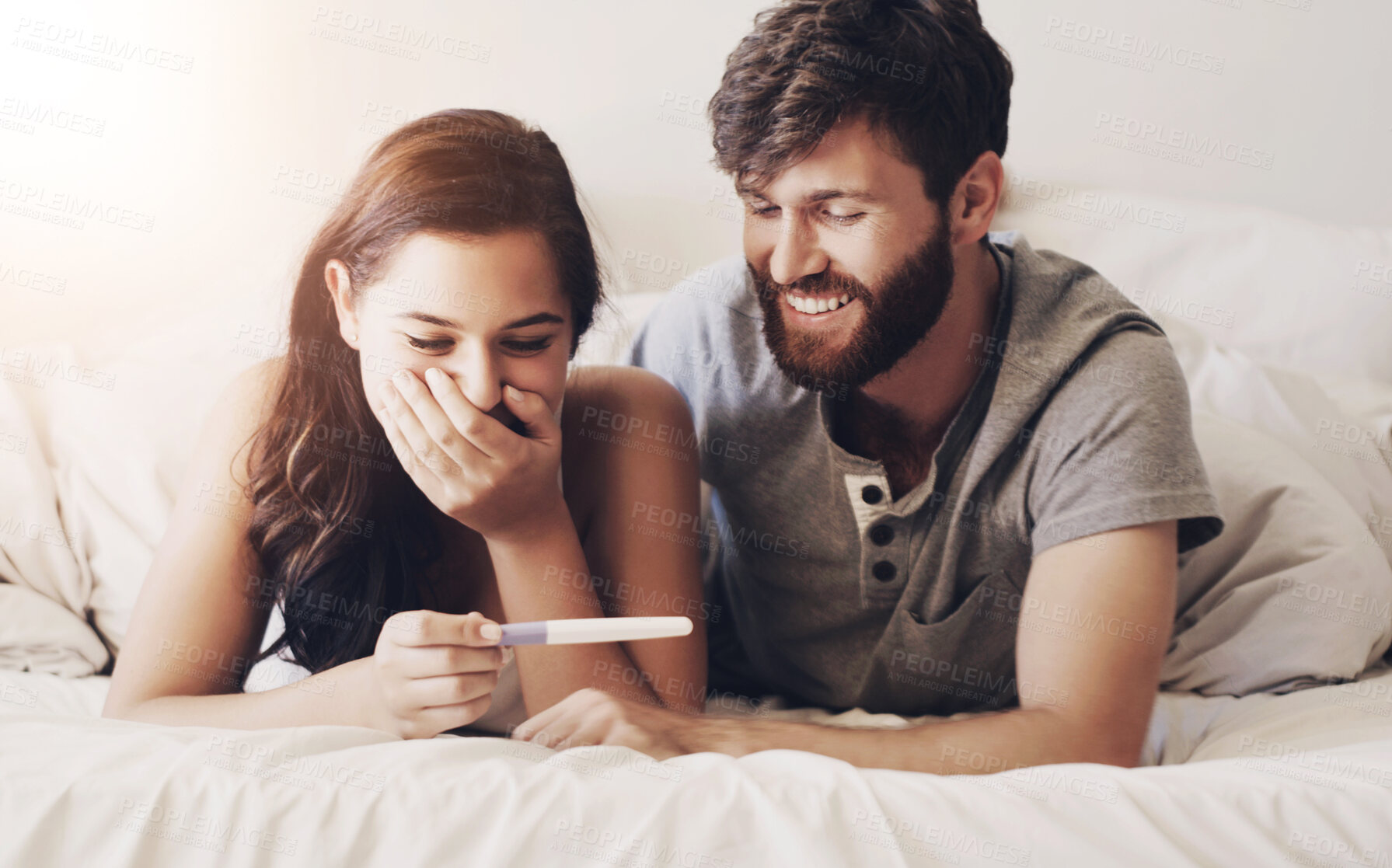 Buy stock photo Happy couple, pregnancy test and bed with good news, results or parenthood together at home. Excited or young man and pregnant woman in shock for maternity, positive or family in bedroom at house