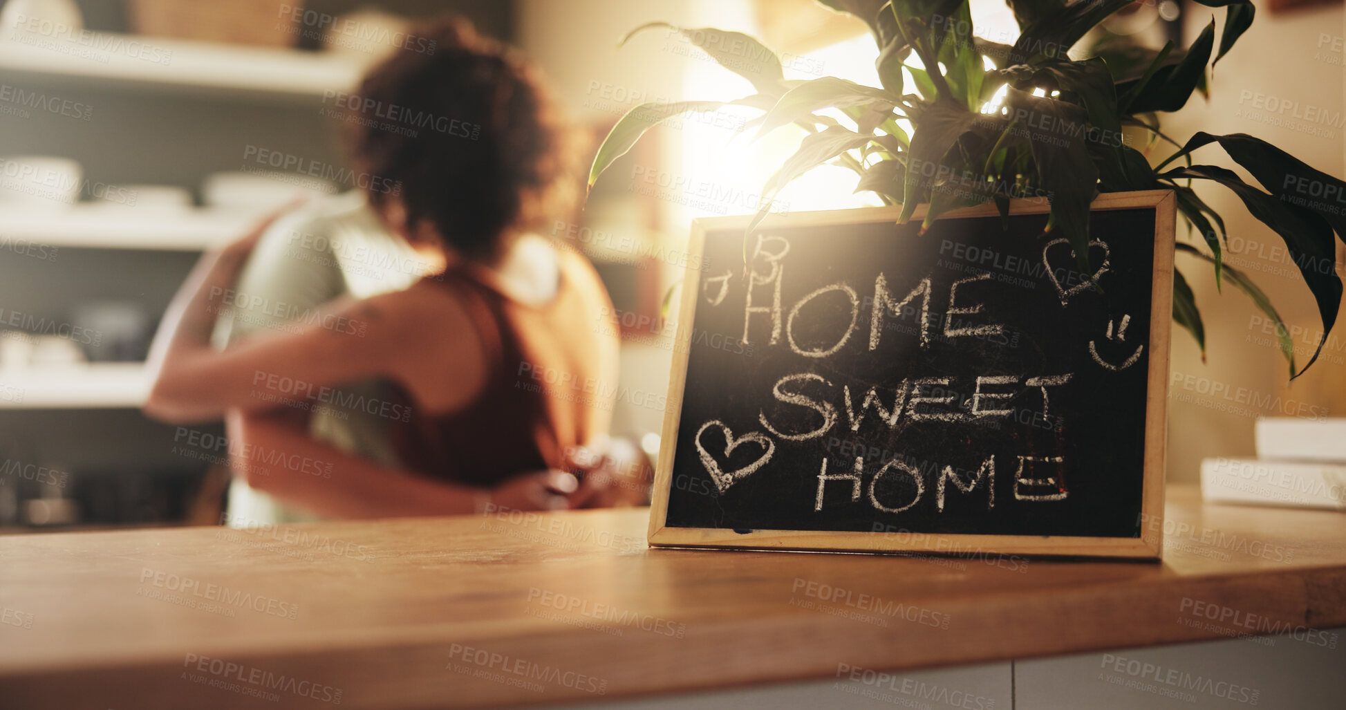 Buy stock photo Couple, hug and love with welcome home sign on chalkboard, table or kitchen at house. Woman, poster and billboard with message, note or notification for bonding, care or warm return in living room