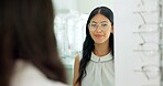 Woman, glasses and mirror at store for eye care, vision and wellness for eyesight, smile and choice. Person, customer and check reflection with decision for optometry, happy and style at retail shop