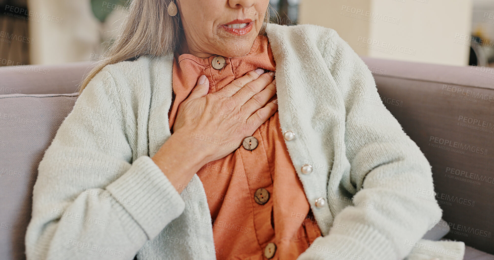 Buy stock photo Heart attack, chest and hands of person, elderly and stress in living room, panic and senior woman. Lounge, medical and emergency for grandmother in house, heartburn and pain of old age on couch