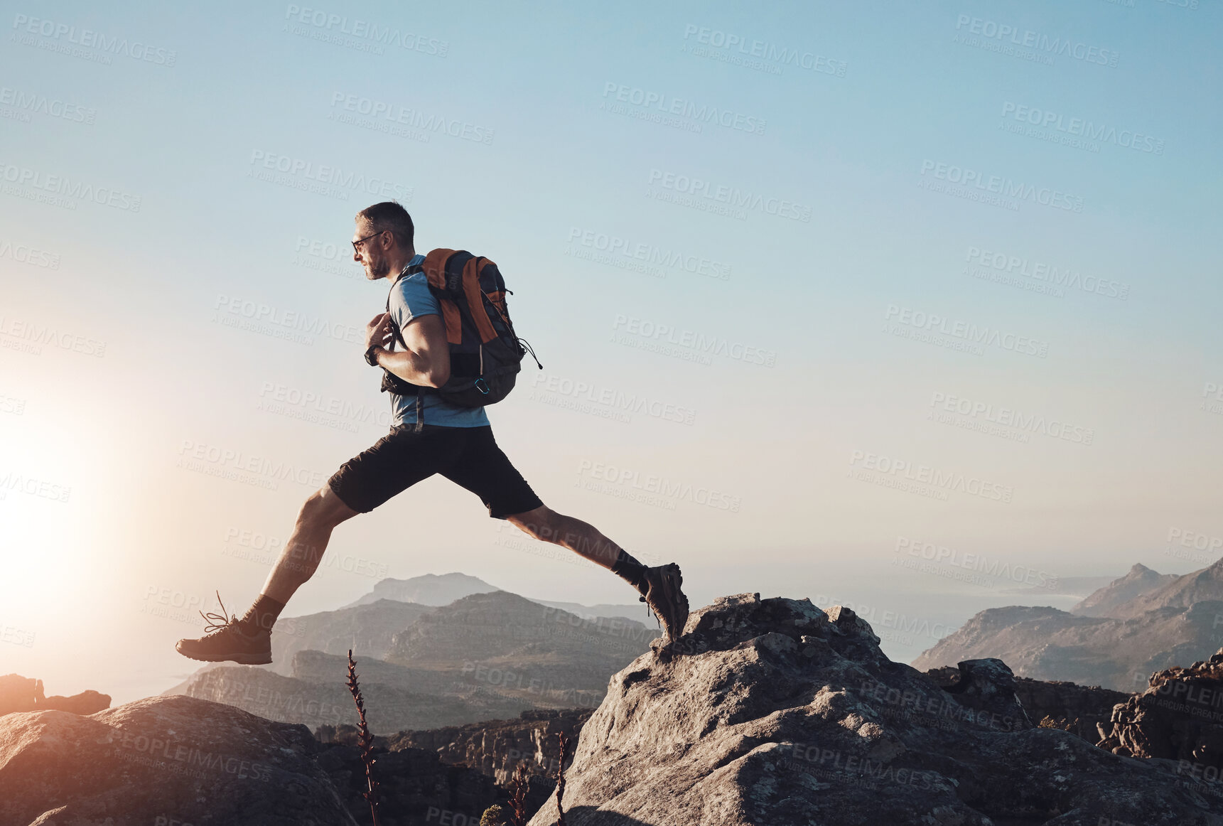 Buy stock photo Hiking, man and jump on mountain for fitness, wellness and energy at sky mockup. Trekking, male athlete and confident on rocks with risk, travel and adventure in nature space for muscle development