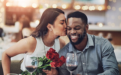 Buy stock photo Couple, dinner and kiss on date in restaurant for flowers, romance or commitment to relationship. Interracial, people and happy with celebration for anniversary, honeymoon or valentines day with wine