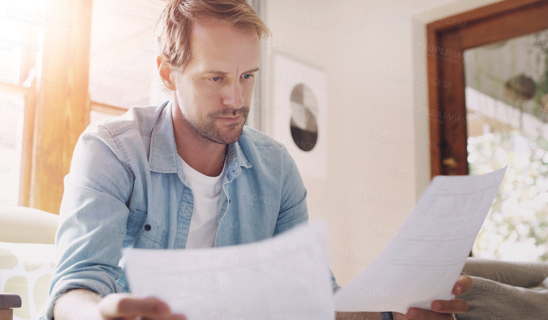 Buy stock photo Man, reading and financial paperwork on sofa for mortgage review, insurance info and bills in home. Guy, documents and check tax statement on couch with loan application, asset management and invoice