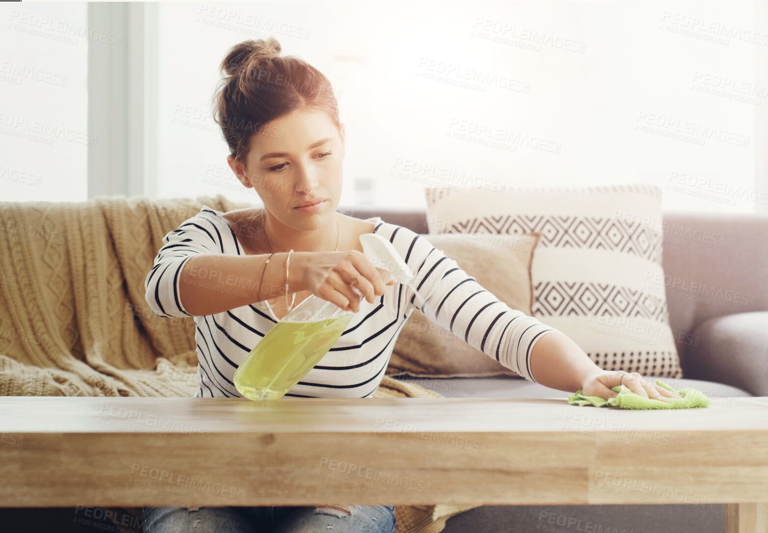 Buy stock photo Shot of a young woman cleaning the table in her living room