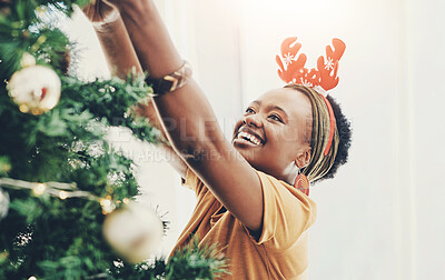 Buy stock photo Happy, celebration and black woman in home with Christmas tree decorating for festive season. Smile, reindeer ears and African female person with xmas holidays for joyful event at house in December.