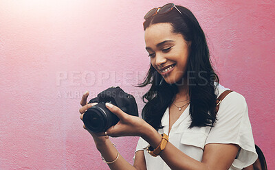 Buy stock photo Cropped shot of an attractive young woman standing alone against a blue background in the city and holding her camera