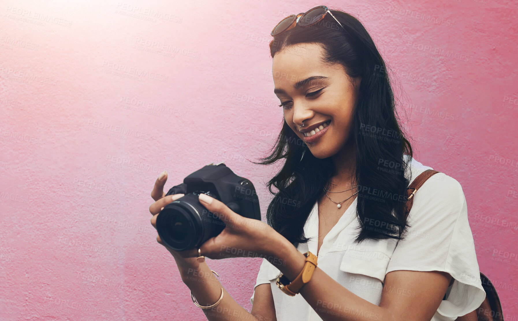 Buy stock photo Cropped shot of an attractive young woman standing alone against a blue background in the city and holding her camera